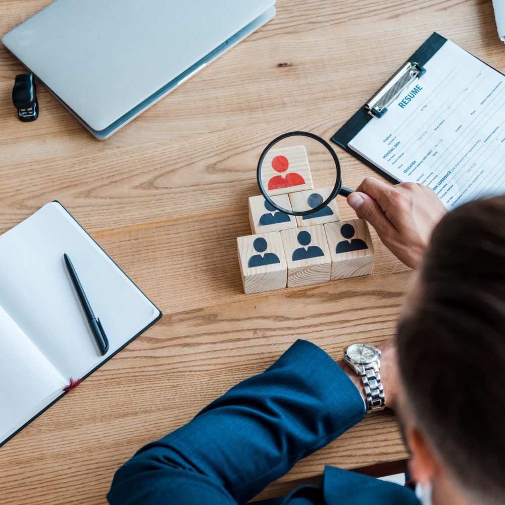 selective-focus-of-recruiter-holding-magnifying-glass-near-wooden-cubes.jpg